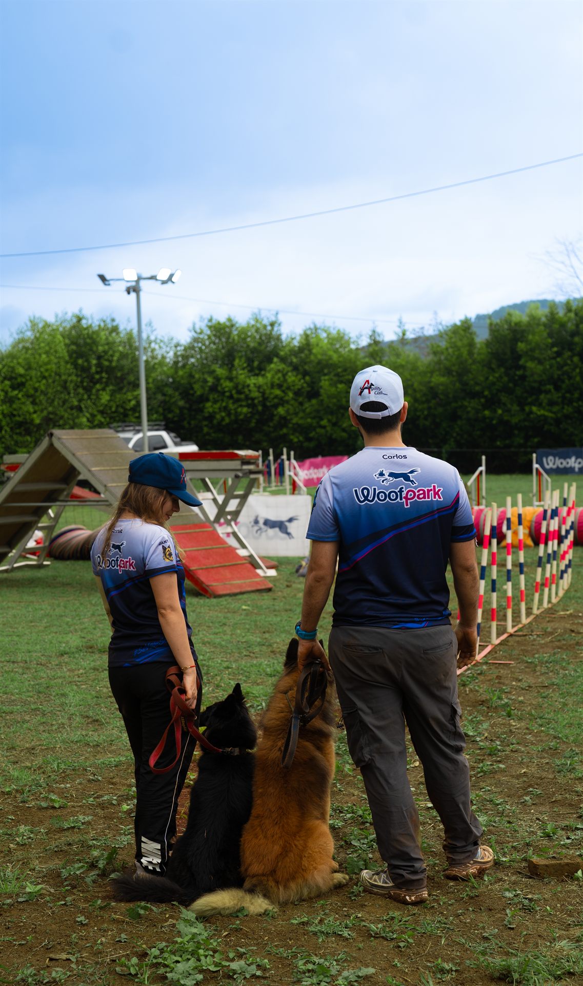 Guías del equipo Agility Cali con sus Pastores Belgas frente al slalom de la pista de deporte canino WPark
